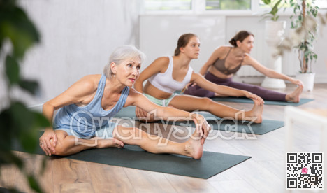 Yoga class of sports women performing Head to Knee Forward Bend Pose, or Janu Sirsasana after practicing together