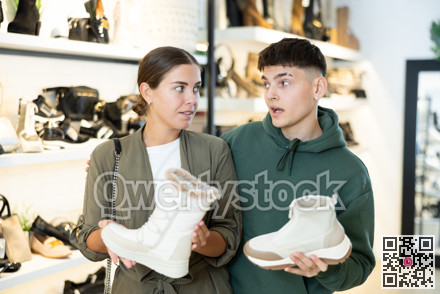 Young couple discussing choice of winter womens boots in shoe store