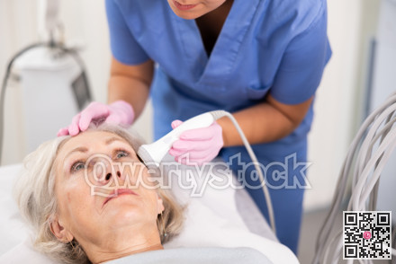 Old woman having face laser therapy procedure
