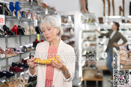 Elderly woman chooses ballet flats in shoe store