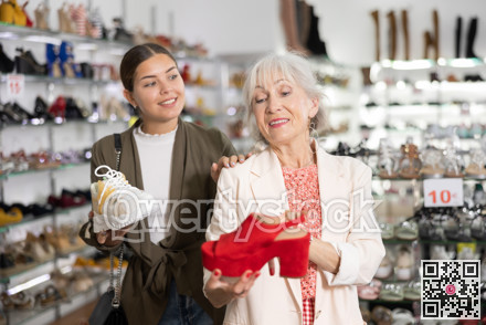 Mom with an adult daughter choose and buy fashionable high heeled shoes in a shoe store