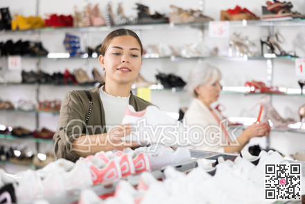 Young woman chooses sneakers in shoe store