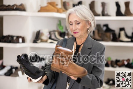 Mature woman takes samples from showcase and examines shoes
