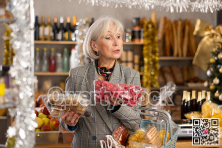 While shopping on eve of New Year holidays, elderly lady buys sweets for festive party