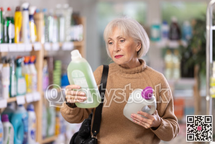 Mature positive woman consumer with household chemical products for washing indoors