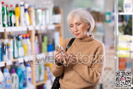 Elderly housewife chooses perfume or aromatic incense in supermarket