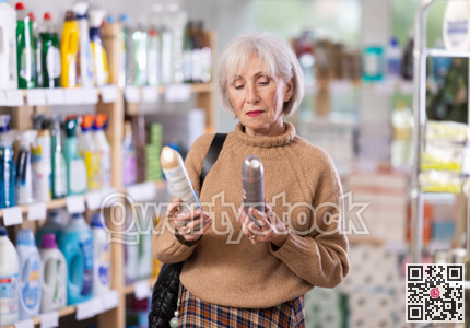 Mature woman choosing hair spray in department store