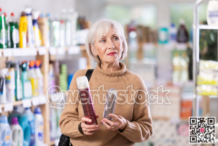 Choosing hairspray in supermarket - mature woman making choice