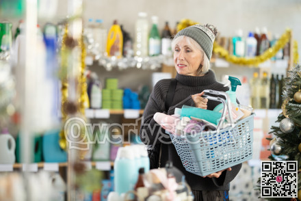 Portrait of happy woman with shopping basket in supermarket before Christmas