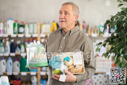 Senior man studies label and choose shower cosmetic present, packaged in basket.
