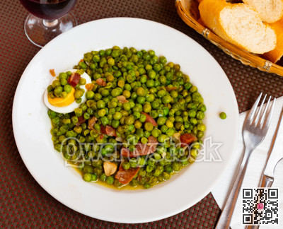 Just cooked green peas with ham and egg on plate