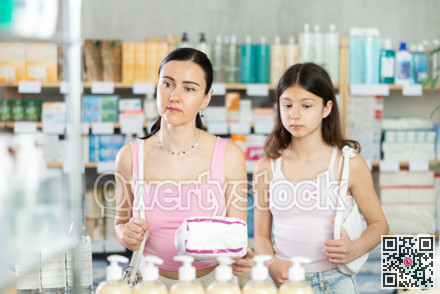 Positive mother and daughter standing at pharmacy or department of household chemicals, choosing feminine pads