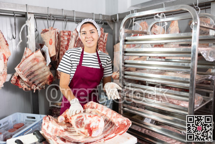 Butchery workwoman preparing fresh veal cuts for sale