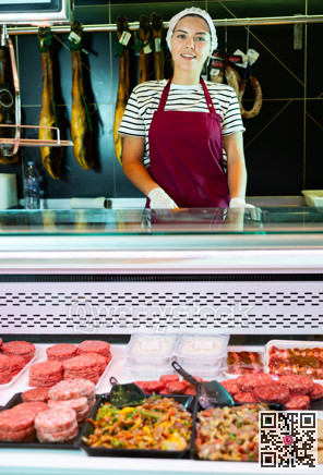 Smiling female butcher holding meat cutlets in meat section of grocery