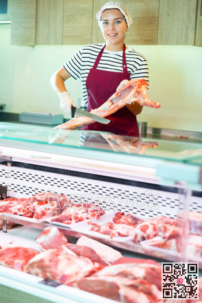 Young saleswoman cutting fresh lamb carcass at counter in butcher store
