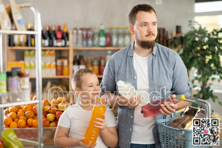 Man with son hold packages plastic bottle and choose consider carbonated beverage in store