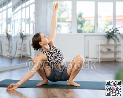 Sporty young woman performing advanced yoga posture in studio