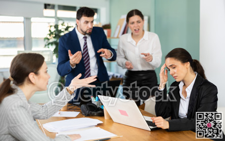 Group of colleagues scolding sad woman in office