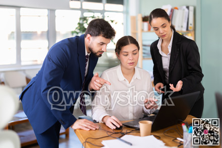 Man and woman help female colleague work with laptop