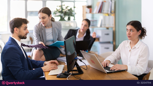 Young woman flirting with male colleague while sitting on office desk photo 3204794