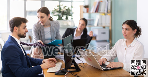 Young woman flirting with male colleague while sitting on office desk photo 3204794