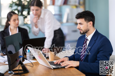 Focused young man working on laptop during busy corporate session
