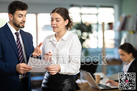 Male and female colleagues looking at document in office