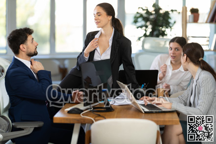 Flirtatious female employee sitting on table and talking to male colleague