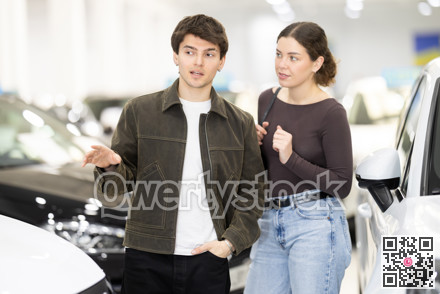 Young couple choosing car at auto dealership