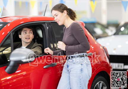 Young couple choosing car at auto dealership