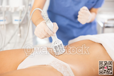Aesthetician administering cold hammer therapy on female client belly