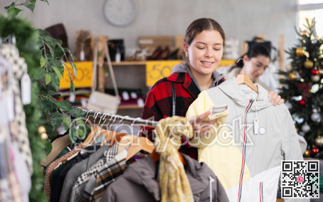 Young girl near showcase pick out and buying down jacket, New Year eve