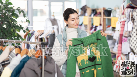 Girl chooses fashionable sweater in clothing store