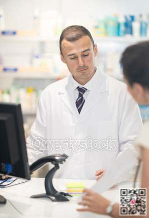 Male pharmacist at the cash register selling medicine to pharmacy visitor