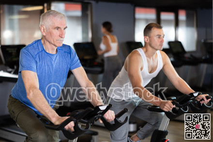 Two men exercising on stationary exercise bikes in gym