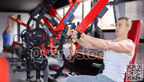 Young man trains his arms on machine