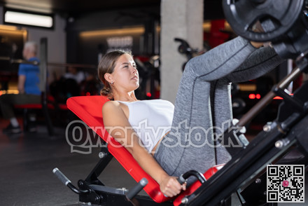 Young woman training her legs with barbell