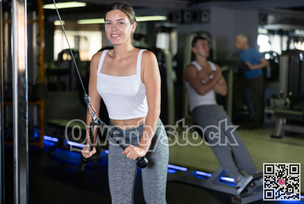 Young woman training with straps in gym