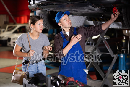 Car service mechanic explains to girl what part is broken in her car