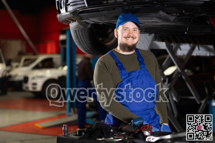 Young guy mechanic posing at car service station