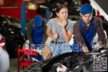 Skilled male auto mechanic controlling automobile detail while young girl looking at it disappointedly