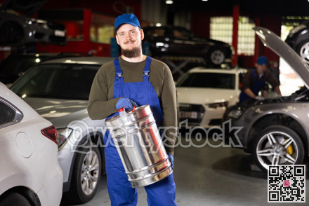 Positive male worker of car workshop holding metal fuel canister