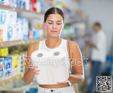 Female customer in store chooses package of toilet paper