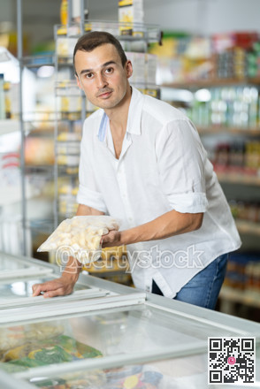 Man standing at refrigerator, choosing frozen convenience food