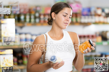 Girl buyer chooses between variation of sauce in shop