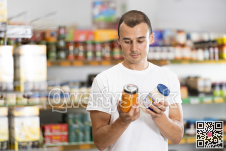 Man selects sauce from glass jars in the produce section of supermarket