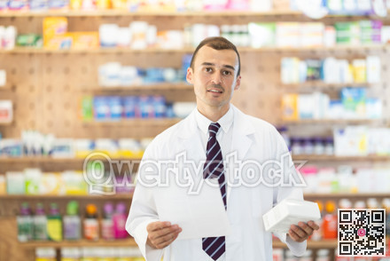 Young male pharmacist standing in drugstore with medicament and recipe in hands