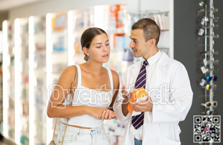 Male pharmacist consulting young girl about medicament in box