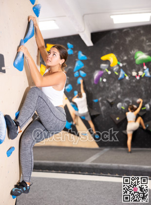 Young woman practicing rock climbing on climbing wall