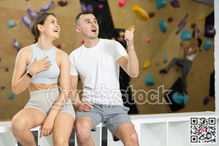 Young man and woman talking near climbing wall